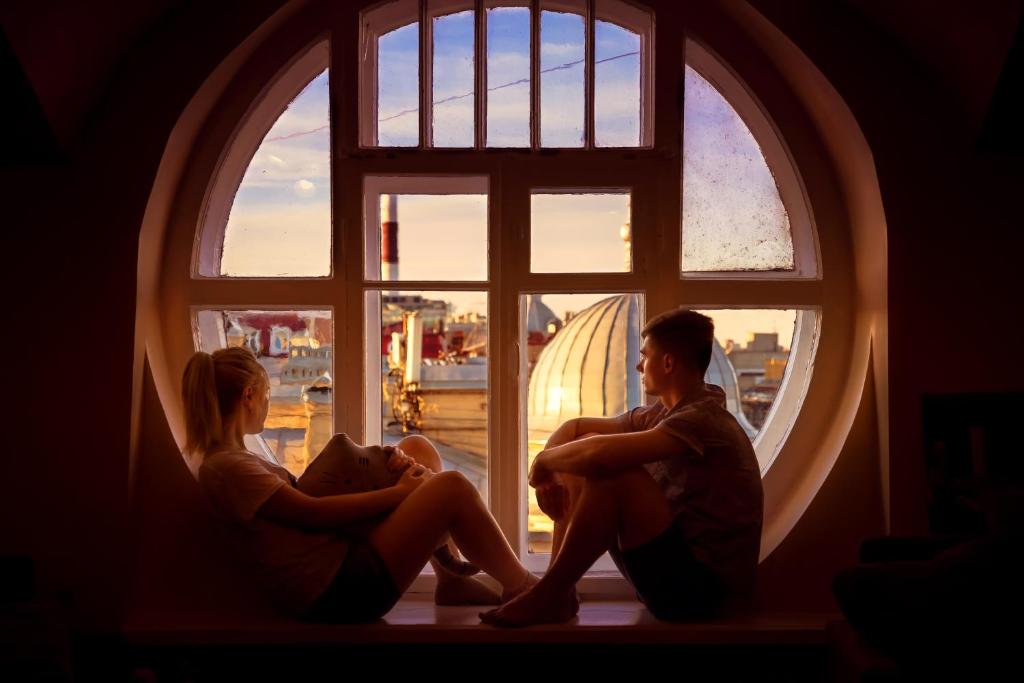 dos personas sentadas frente a una ventana en Hostel na Nevskom Mishanya, en San Petersburgo
