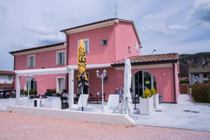 a red building with white chairs and umbrellas in front at B&B SILVIA in Vecchiano