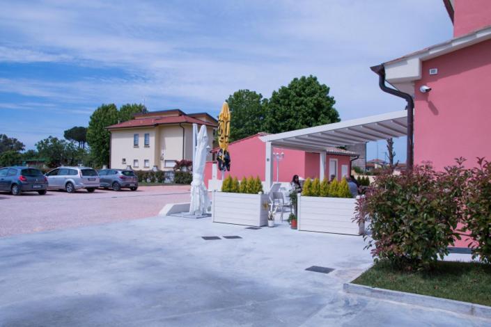 a parking lot with a pink building and cars at B&B SILVIA in Vecchiano