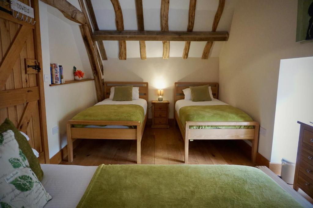 Duas camas num pequeno quarto com pisos em madeira em Hopeend Holidays Cottage em Great Malvern