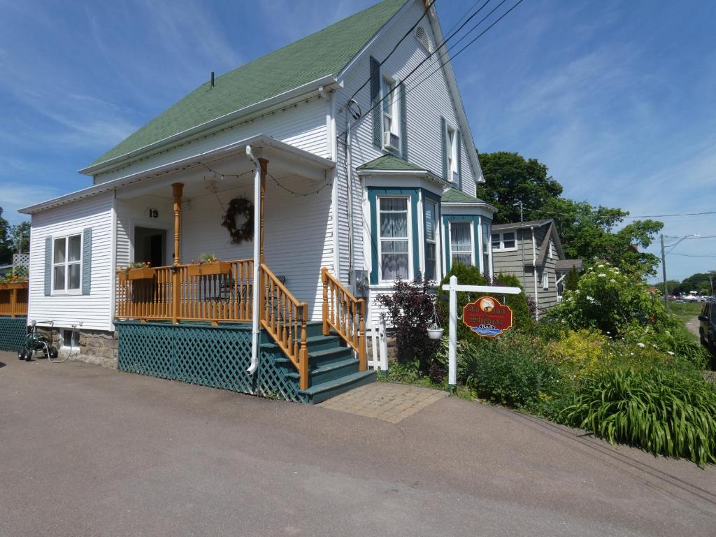 a white house with a green roof and a porch at LaCasa enShediac in Shediac