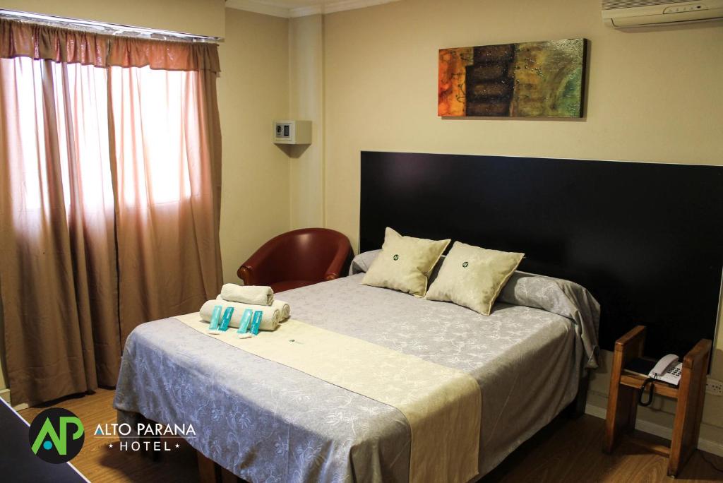 a bedroom with a bed with a chair and a window at Hotel Alto Parana in Córdoba