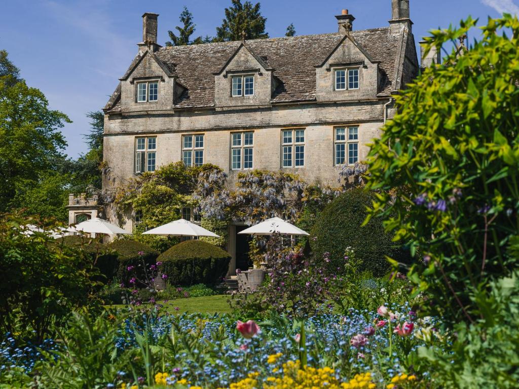 une ancienne maison en pierre avec des parasols dans le jardin dans l'établissement Barnsley House, à Cirencester