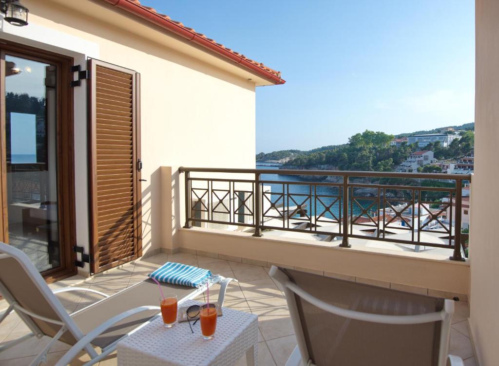 a balcony with a table and chairs and a view of the ocean at Esperides Maisonettes in Votsi