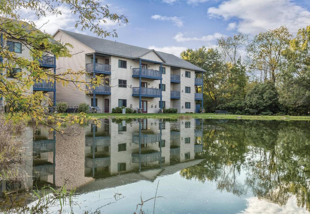 an apartment building with a lake in front of it at Club Wyndham Tamarack in Wisconsin Dells