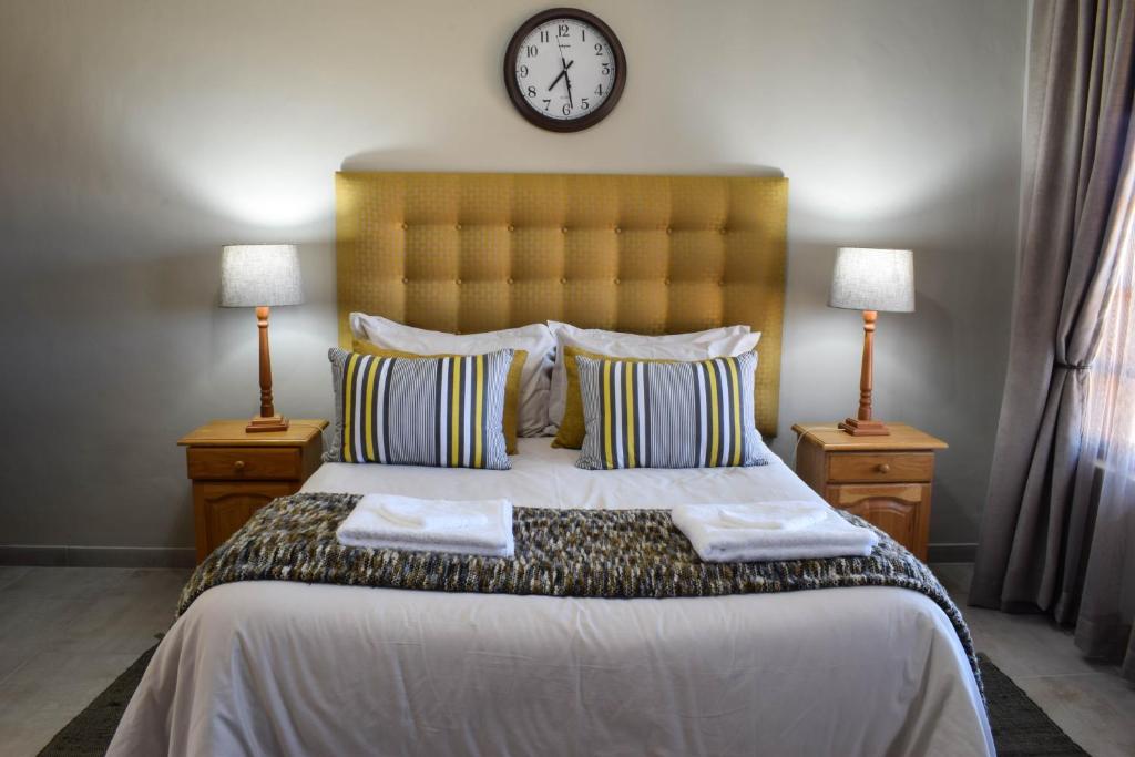a bedroom with a large bed with a clock on the wall at Merino Guest Farm in Clarens