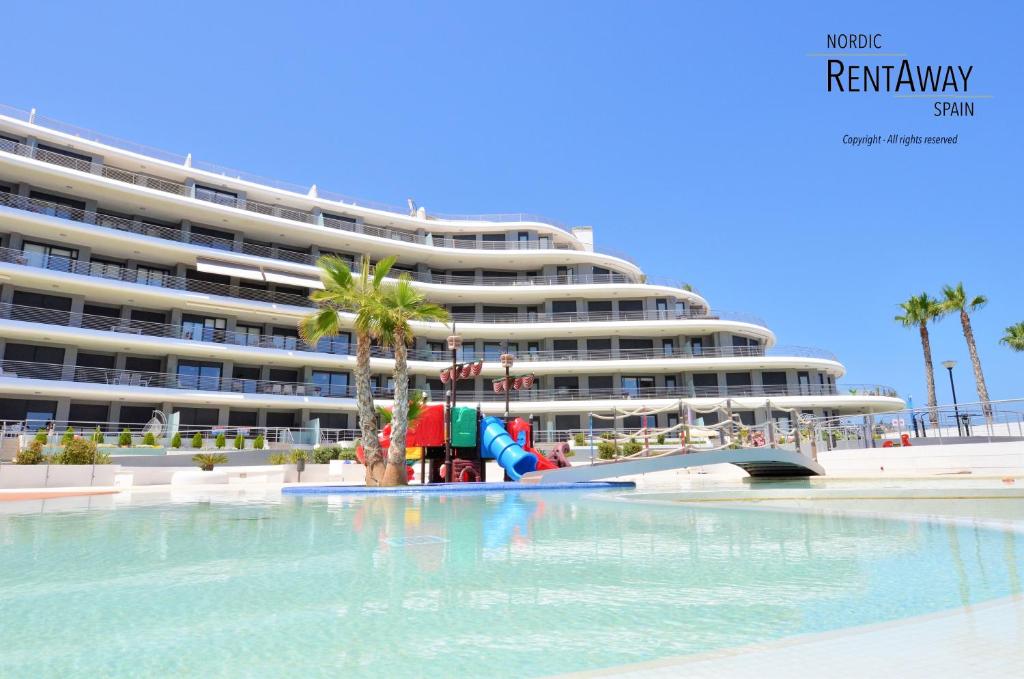 a large building with a pool in front of a beach at Infinity View Apartments by NRAS in Arenales del Sol