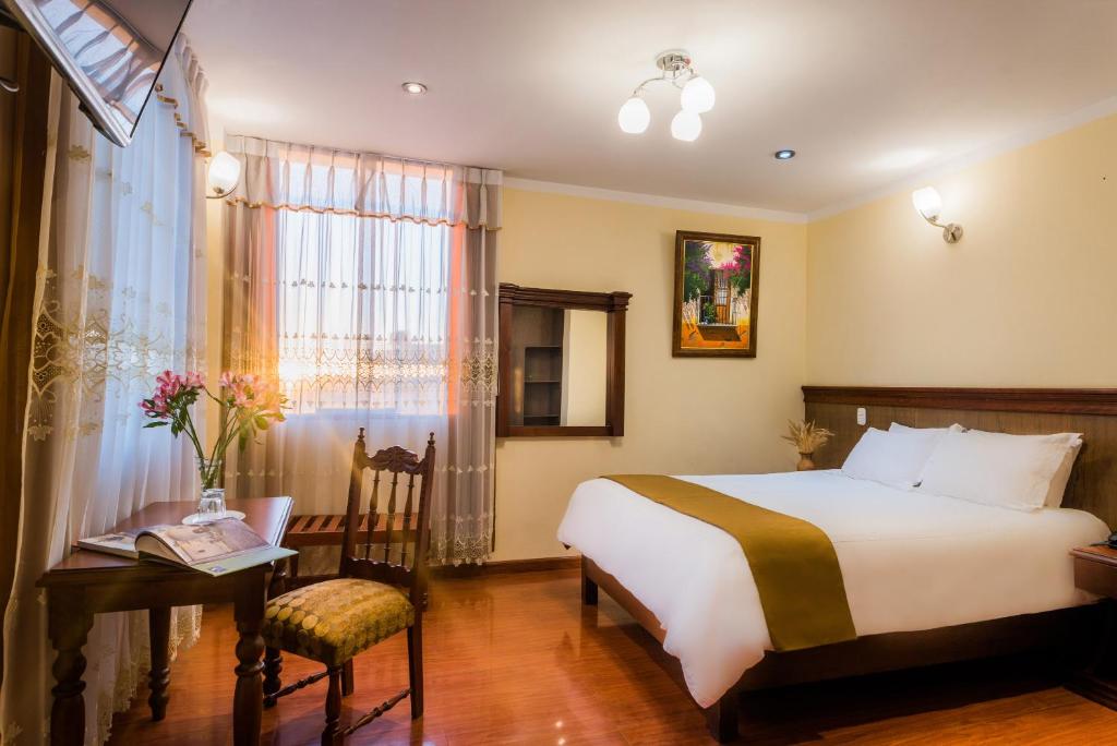 1 dormitorio con cama, escritorio y ventana en Majestad Hotel Boutique, en Arequipa