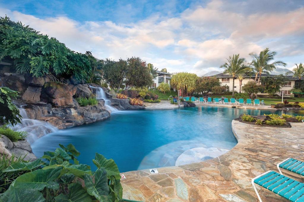 a resort pool with a waterfall and blue chairs at Club Wyndham Bali Hai Villas in Princeville