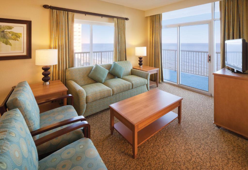 a living room with a couch and a tv and a balcony at Club Wyndham SeaWatch Resort in Myrtle Beach