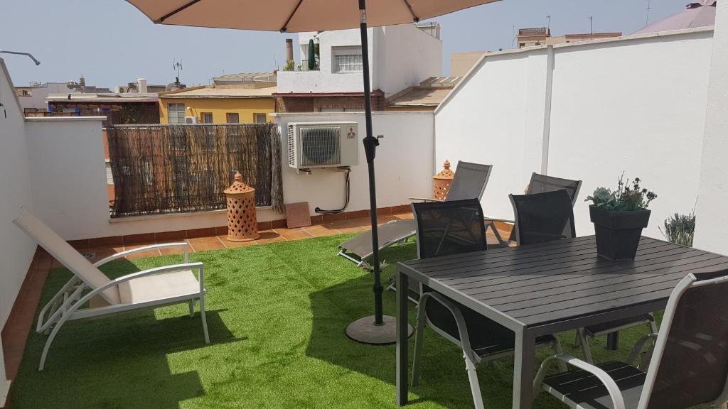 eine Terrasse mit einem Tisch, Stühlen und einem Sonnenschirm in der Unterkunft Malaga Centro Terraza in Málaga