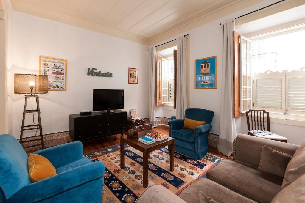 a living room with a couch and chairs and a tv at 2 bedroom apartment with patio next to Avenida da Liberdade in Lisbon