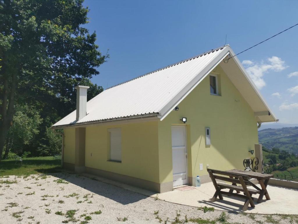 una casa amarilla con un banco al lado en Holiday home Ajla, en Visoko