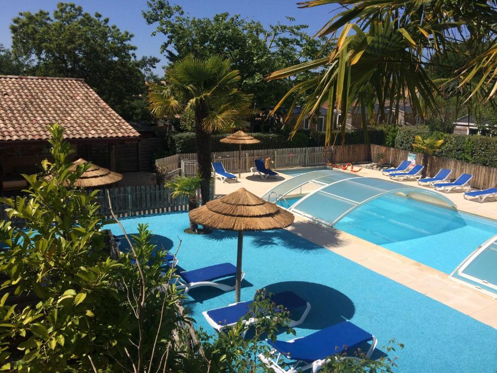a swimming pool with chairs and an umbrella at Appartement Arès - à 900m du Bassin in Arès