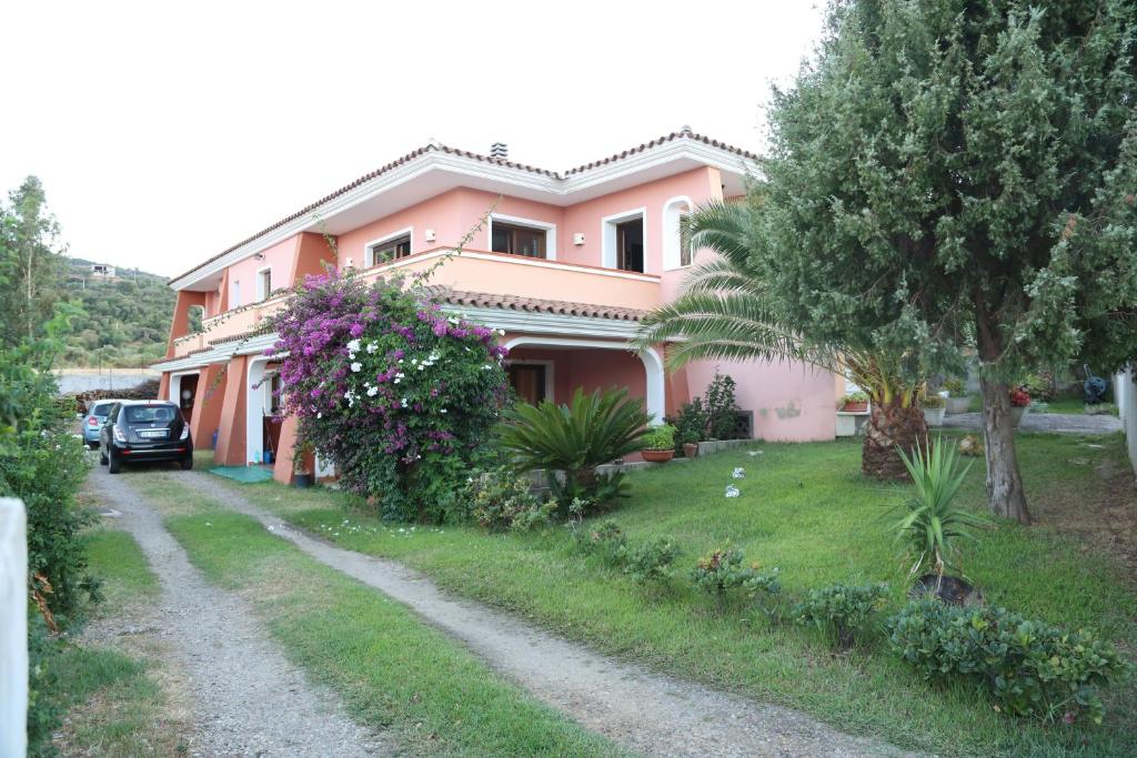 a pink house with a car parked in front of it at B&B Ada in Torpè