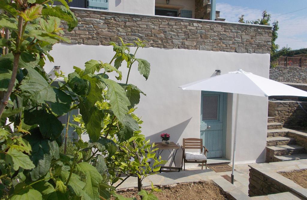 eine Terrasse mit einem Sonnenschirm, einem Tisch und einem Stuhl in der Unterkunft Three Little Roses Country House in Mési