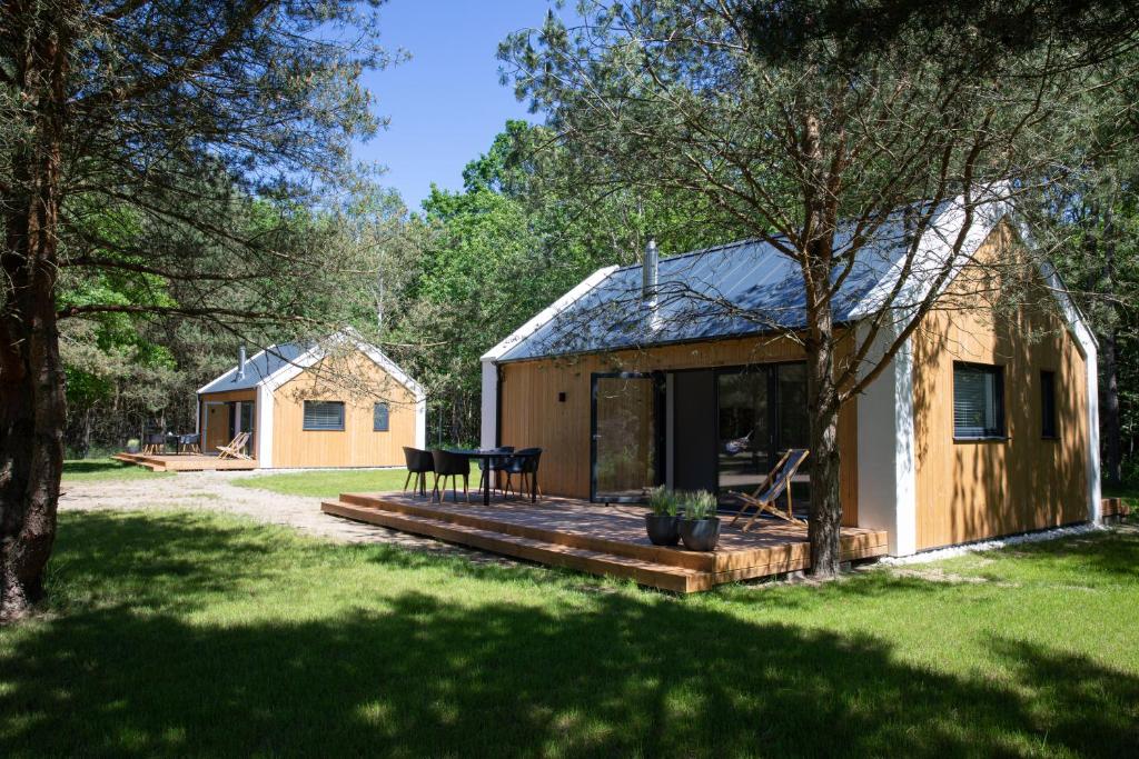 a wooden cabin with a deck in a yard at Słowiński Zakątek in Smołdziński Las