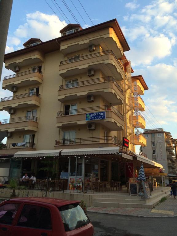 a tall building with a restaurant in front of it at Serendi Apart Hotel in Alanya