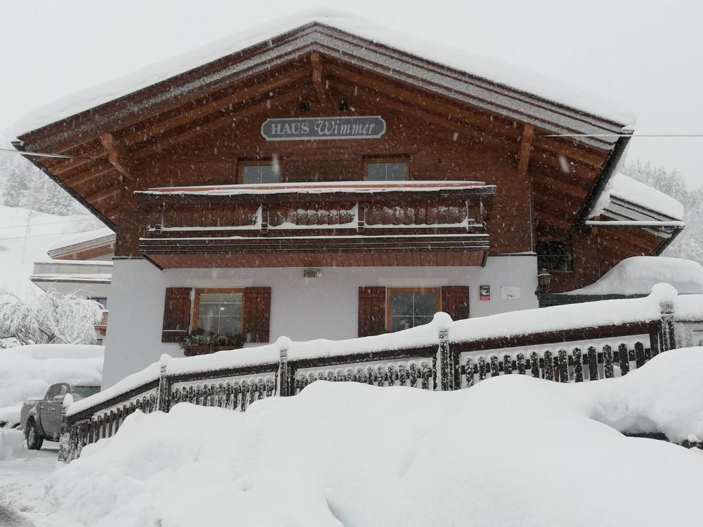 una casa cubierta de nieve con una valla en Haus Wimmer, en Saalbach Hinterglemm