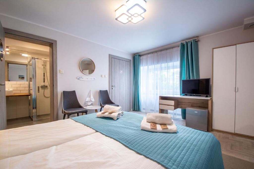 a bedroom with a bed with a desk and a television at Beach House - przy plaży in Sopot