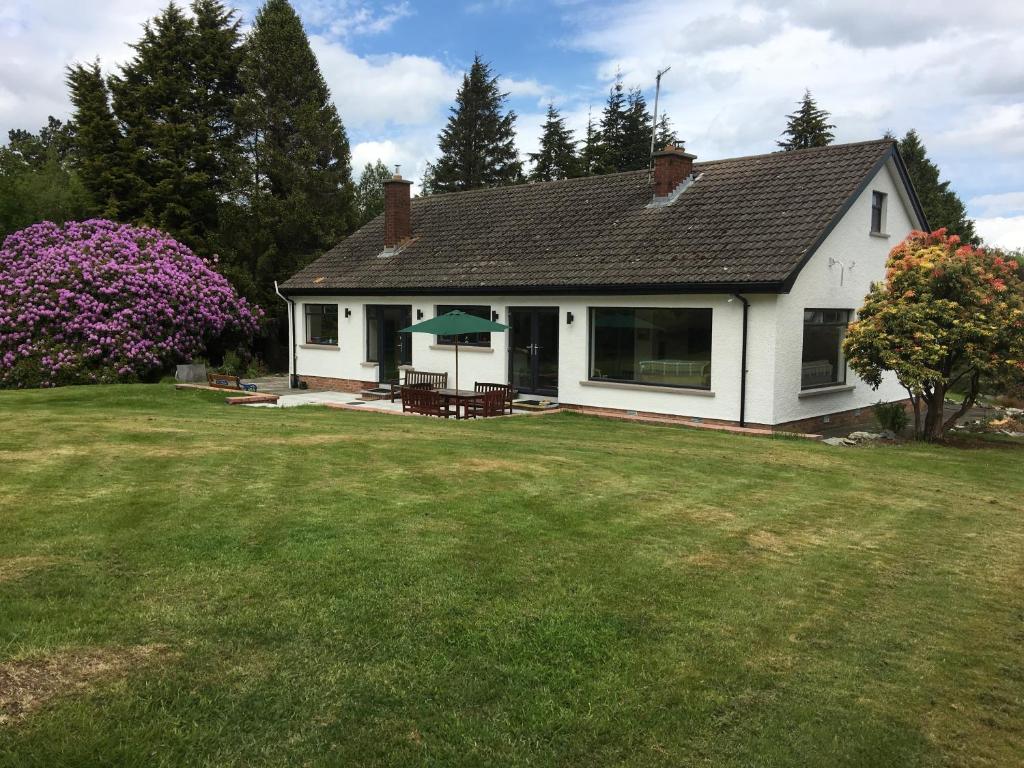 een klein wit huis met een tuin met een gazon sidx sidx bij Larch Lodge in Newcastle