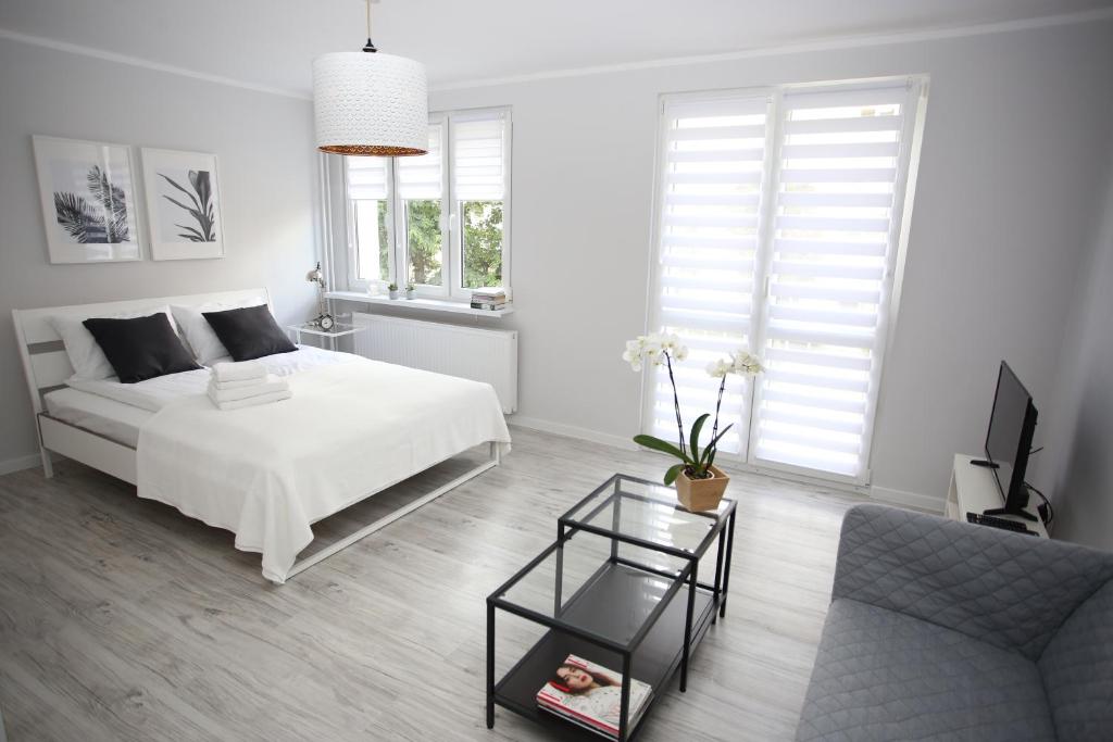 a white bedroom with a bed and a couch at APARTAMENT SŁOBÓDZKIEGO 7 in Świdnica