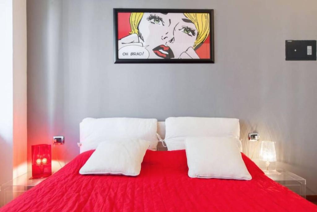 a bedroom with a red bed with a painting on the wall at Pop_house, in the heart of Milano! in Milan