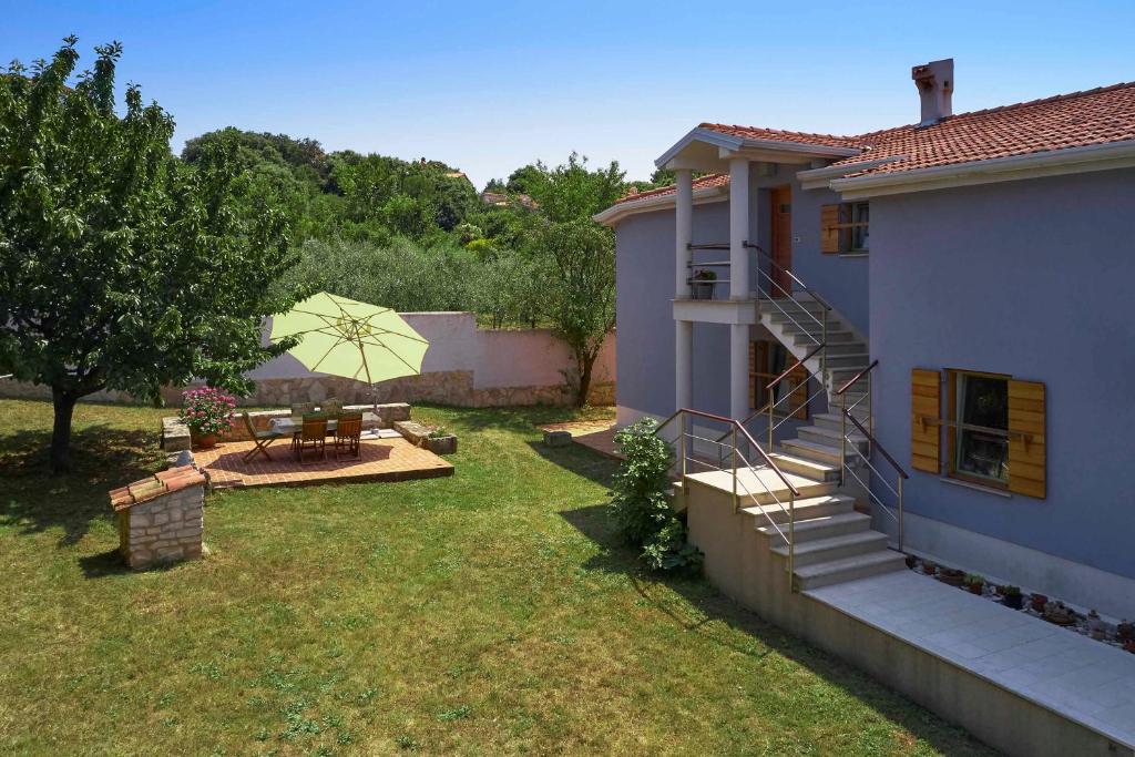 a house with a yard with a table and an umbrella at Villa Giardina Apartments in Vinkuran