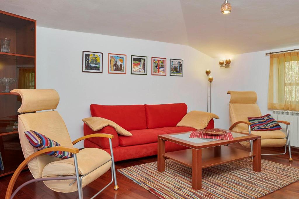 a living room with a red couch and two chairs at Villa Giardina Apartments in Vinkuran