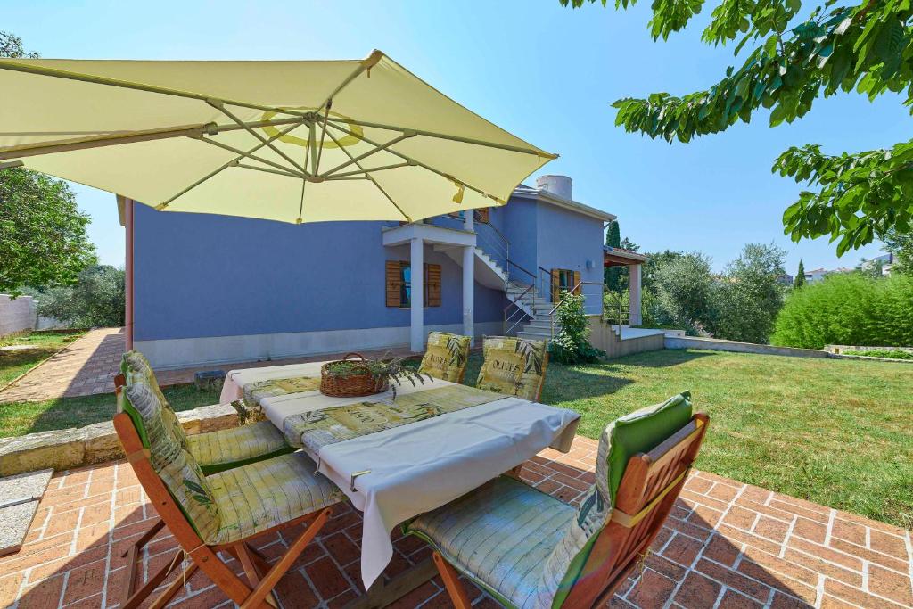 einen Tisch und Stühle mit gelbem Regenschirm in der Unterkunft Villa Giardina Apartments in Vinkuran