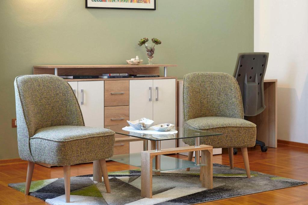 a living room with two chairs and a glass table at Villa Giardina Apartments in Vinkuran