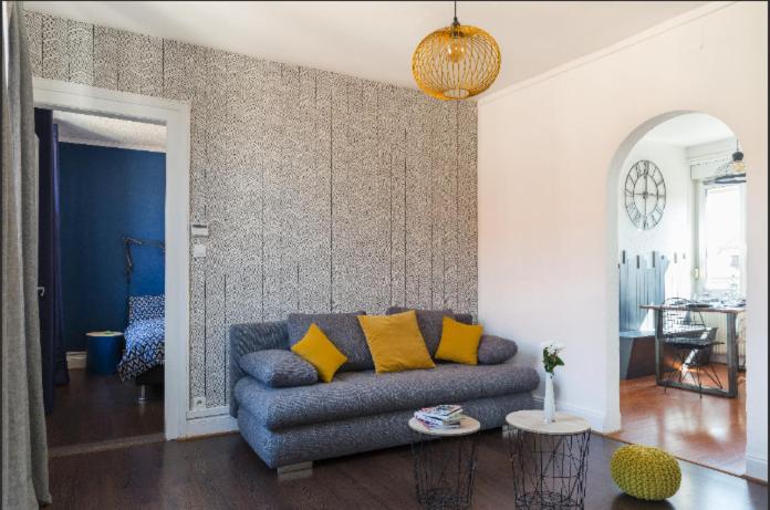 un salon avec un canapé bleu avec des coussins jaunes dans l'établissement Gîte Hopla 2 chambres, à Colmar