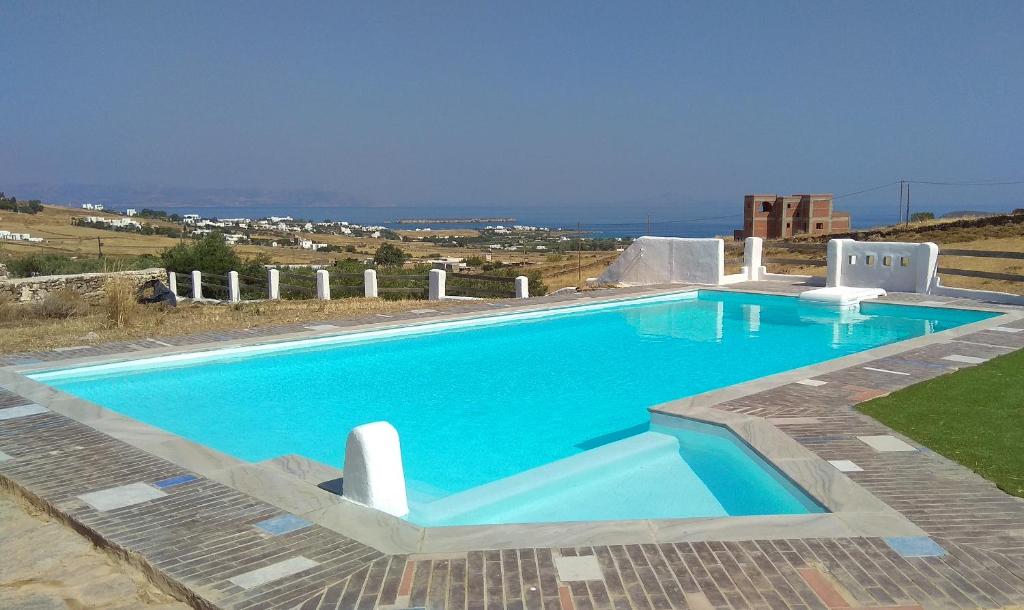 a large swimming pool with blue water in a yard at Elysium Paros Houses in Chrissi Akti
