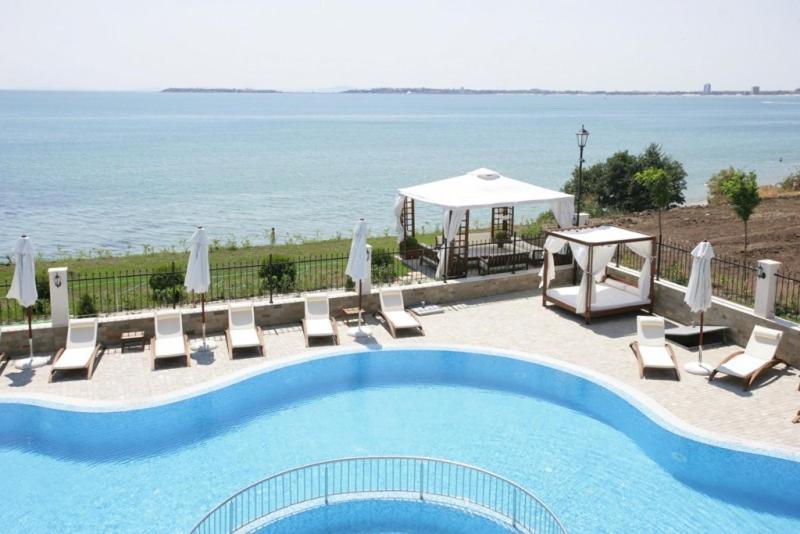 una piscina con sillas, un cenador y el océano en Coastal Dreams complex en Sveti Vlas