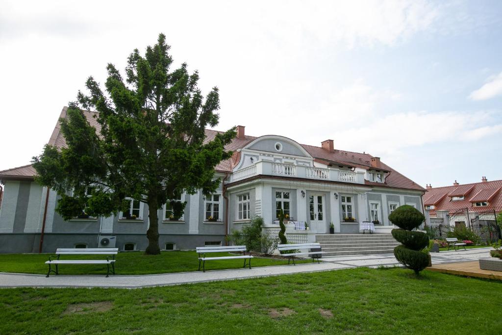 um grande edifício branco com bancos em frente em Mazurski Dwór em Olecko