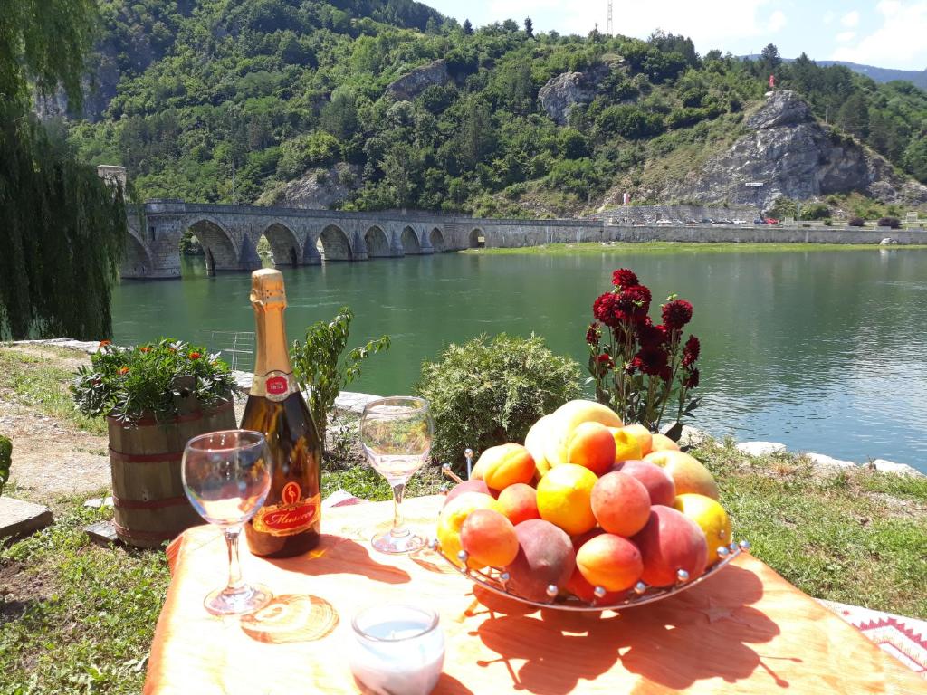 a table with a bowl of fruit and a bottle of wine at Apartment Lotika in Višegrad