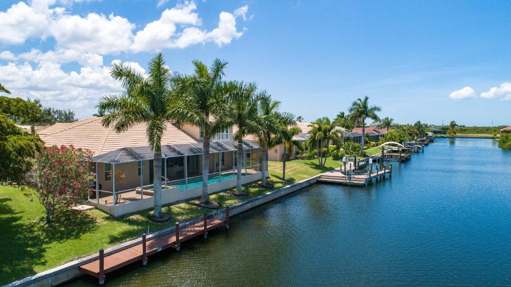 a house on a dock next to a body of water at Mangrove Bay SW Cape - waterfront private home locally owned & managed, fair & honest pricing in Cape Coral