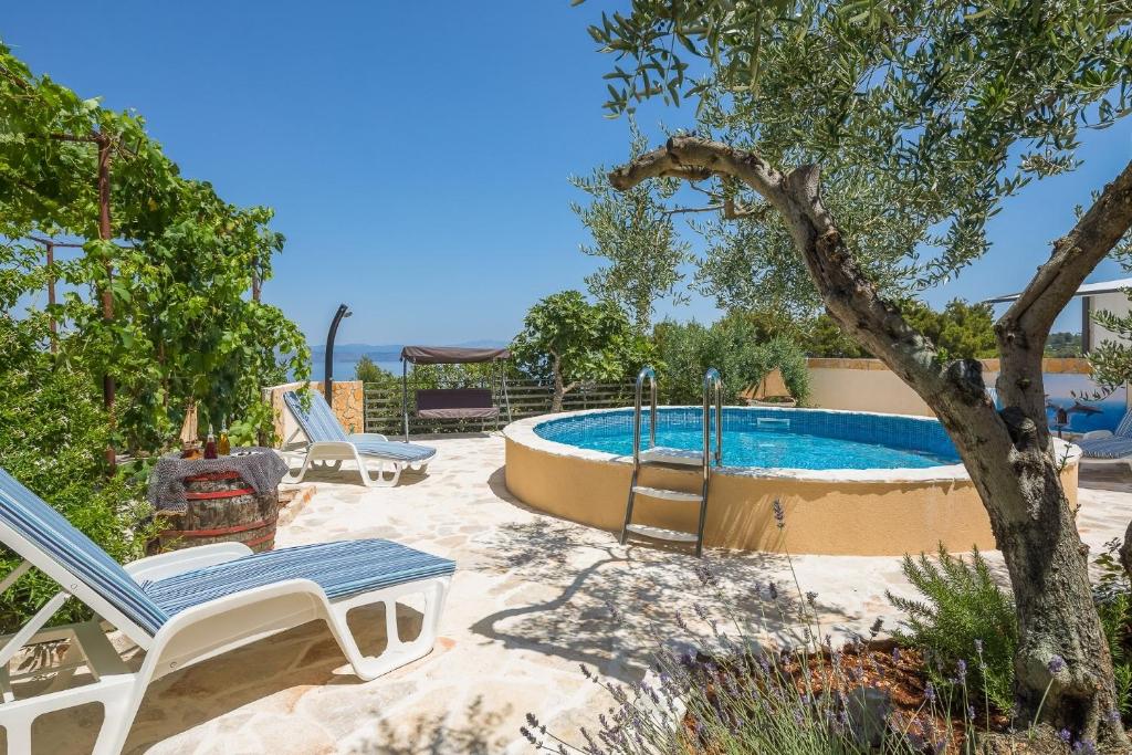 a patio with a pool and a chair and a tree at Villa Ante - with pool in Rogač