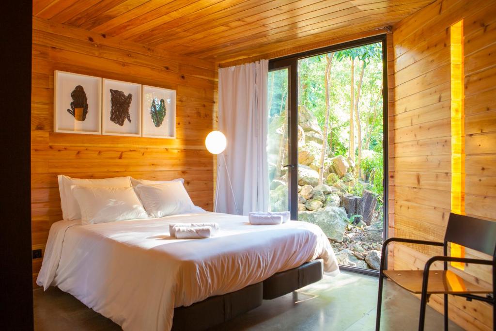 a bedroom with a bed and a large window at Caparica Azores Ecolodge in Biscoitos