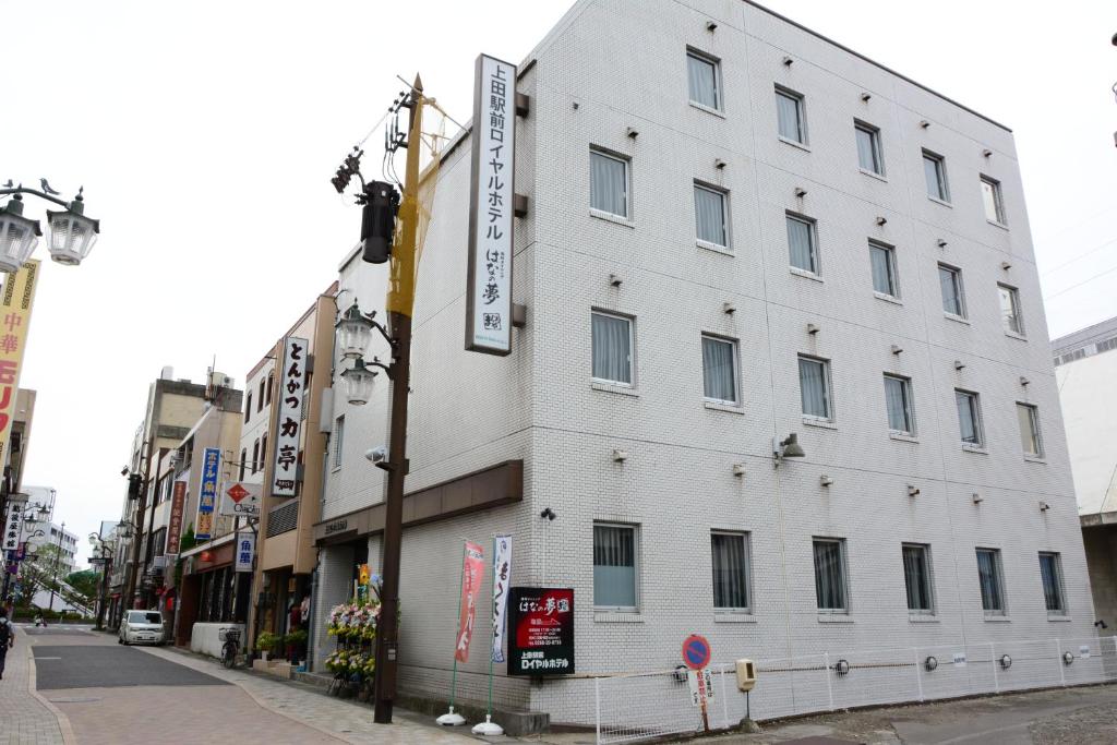 ein weißes Gebäude an der Straßenseite in der Unterkunft Ueda Ekimae Royal Hotel in Ueda