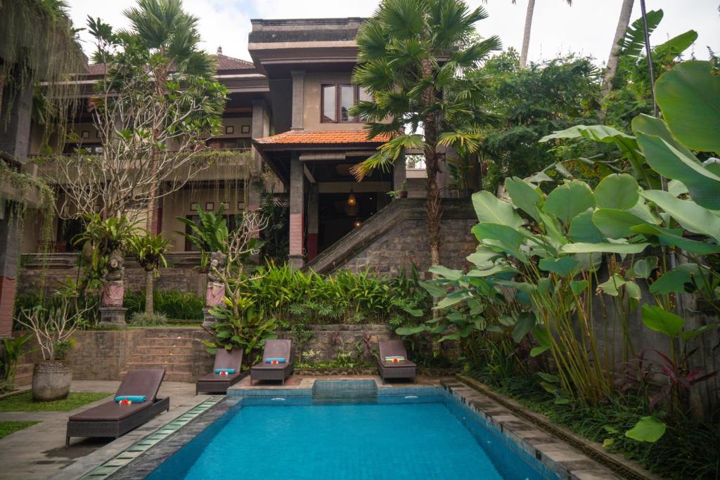 a villa with a swimming pool in front of a house at Alam Terrace Cottages in Ubud