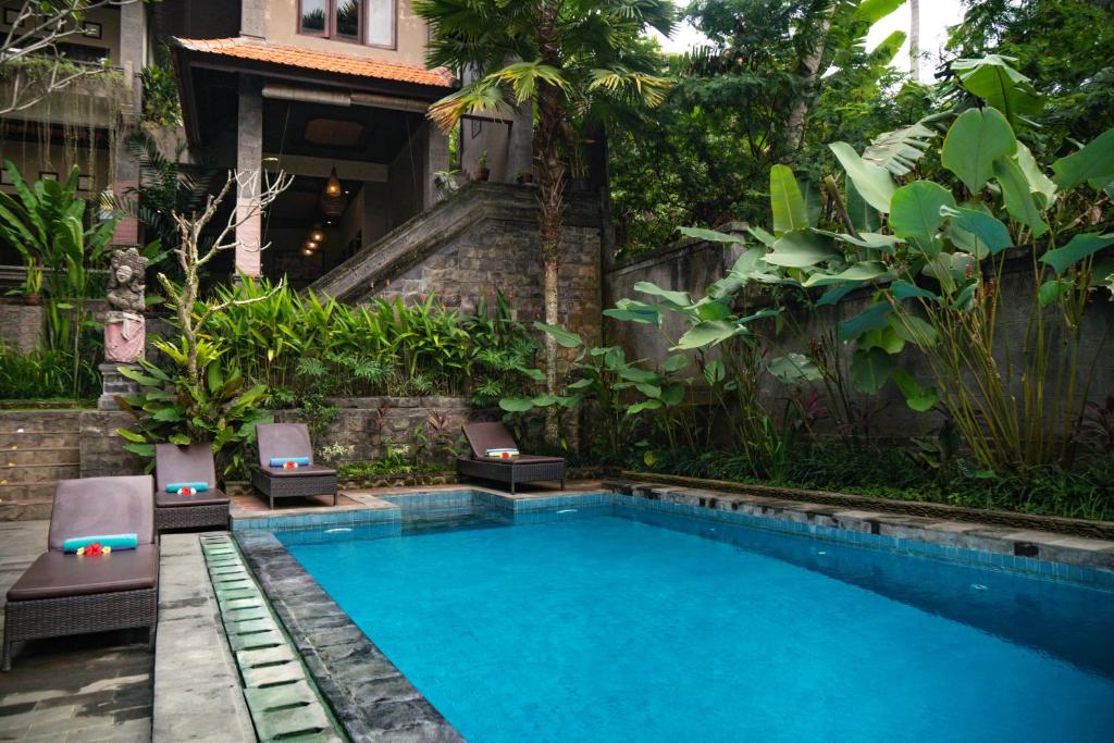 a swimming pool in the middle of a garden at Alam Terrace Cottages in Ubud