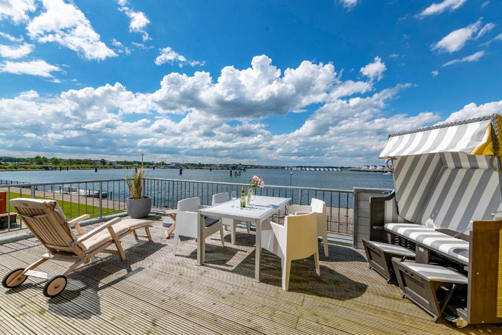 a deck with a table and chairs and a view of the water at La Maisonnette in Olpenitz