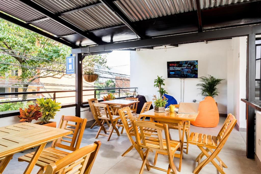 メデジンにあるMedellin Backpacker Hostelの木製のテーブルと椅子、バルコニーが備わるレストランを提供しています。