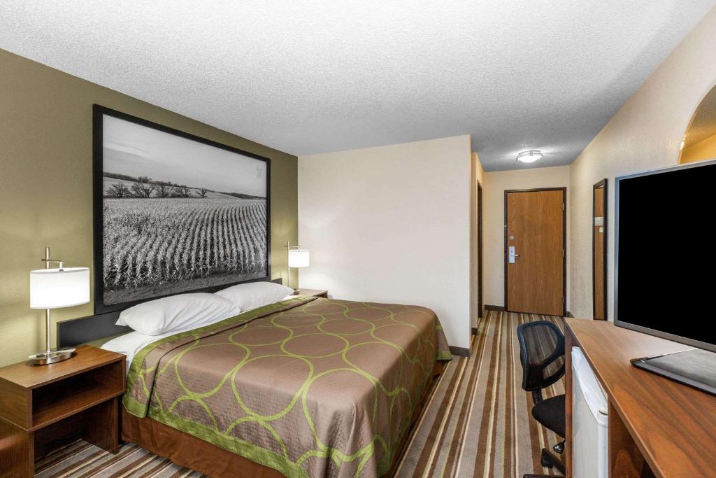 a hotel room with a bed and a flat screen tv at Super 8 by Wyndham Storm Lake in Storm Lake