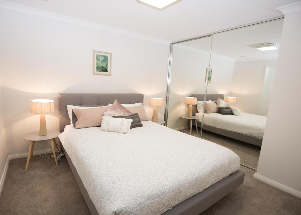 a bedroom with a large white bed and a mirror at Yaran Suites in Rockingham