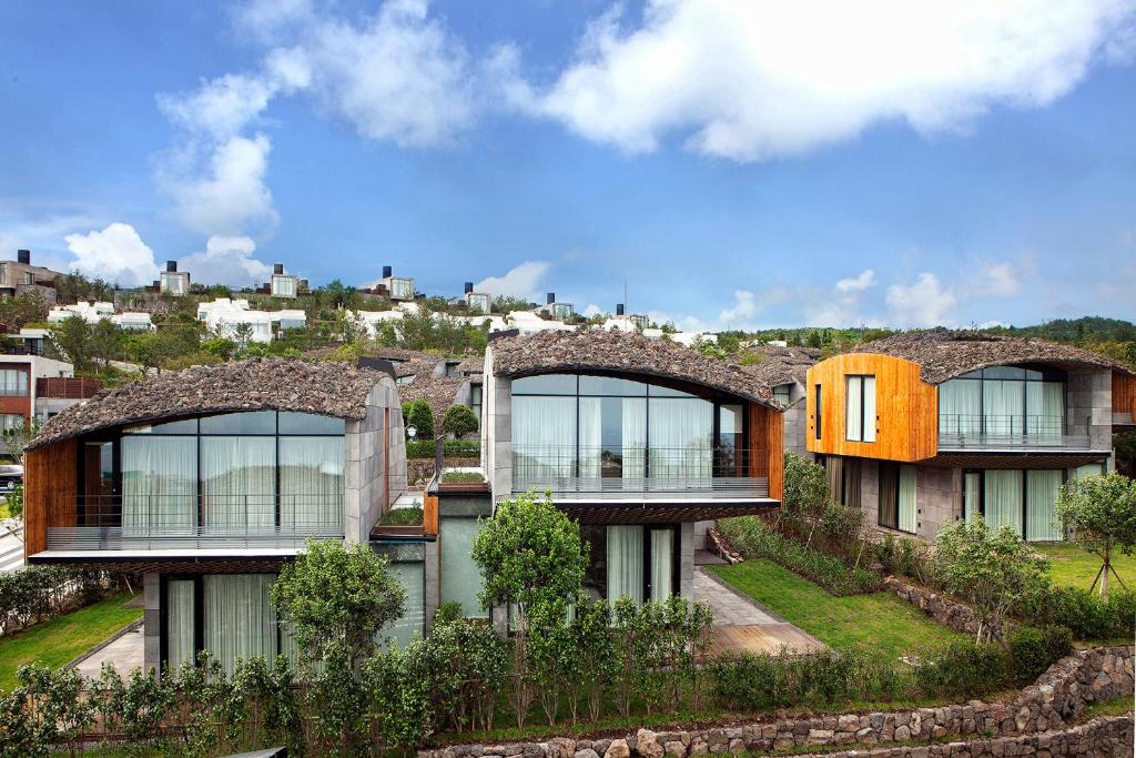 Lotte Resort Jeju Artvillas في سيوجويبو: منزل كبير مع نوافذ على قمة تلة