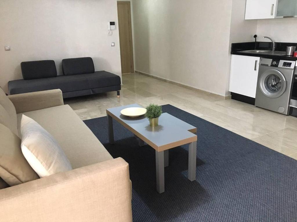 uma sala de estar com um sofá e uma mesa em Appartement près de Novotel face au parc em Mohammedia