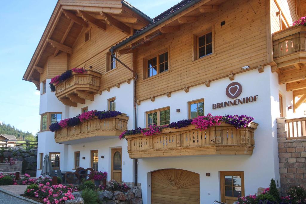 a building with wooden balconies and flowers on it at Appartementhaus Brunnenhof in Wagrain