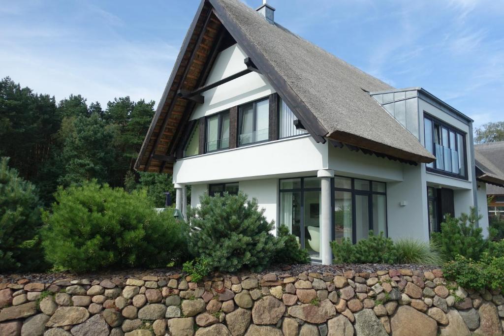 a house with a slate roof and a stone wall at 5 Sterne Luxusdomizil im Dünenland in Ostseebad Karlshagen